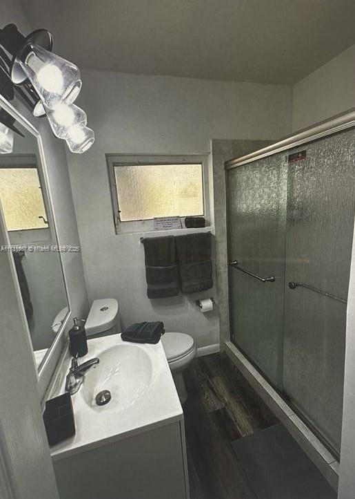 bathroom with an enclosed shower, vanity, a wealth of natural light, wood-type flooring, and toilet