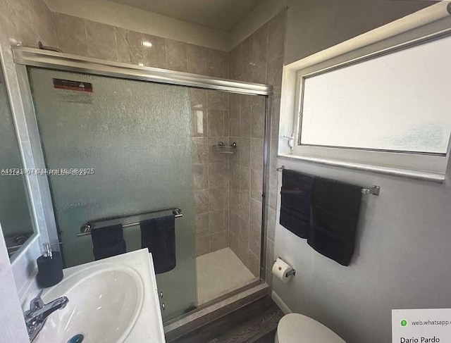 bathroom with toilet, a shower with shower door, and sink