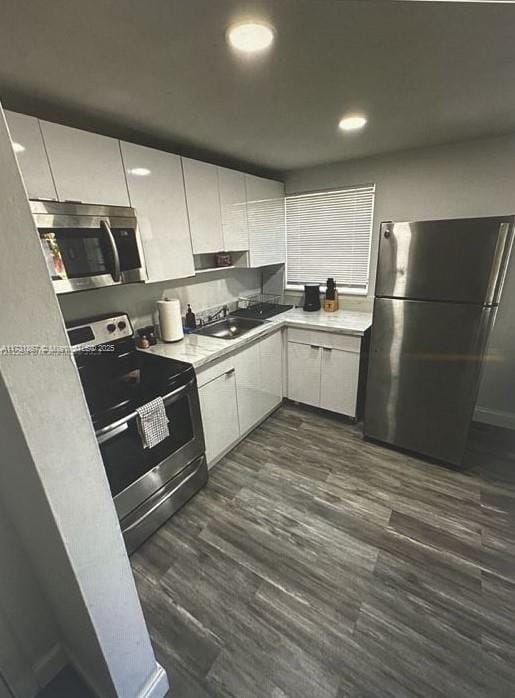 kitchen featuring dark wood-type flooring, stainless steel appliances, sink, and white cabinets