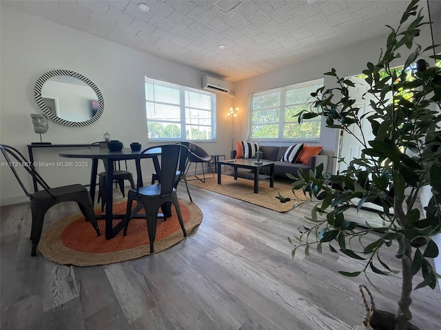 dining area with a wall mounted air conditioner and light hardwood / wood-style flooring