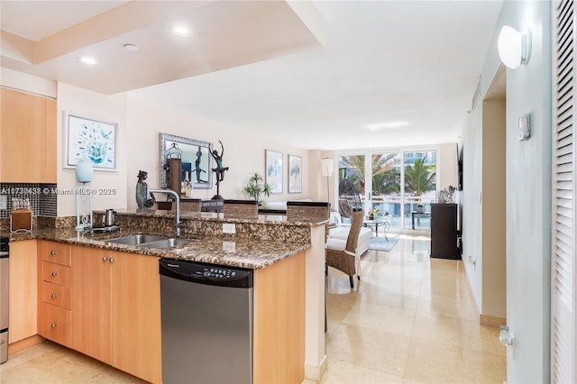 kitchen featuring dishwasher, sink, dark stone countertops, expansive windows, and kitchen peninsula