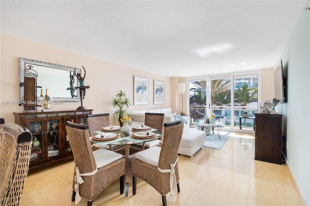 dining area with light tile patterned floors, a wall of windows, and a textured ceiling