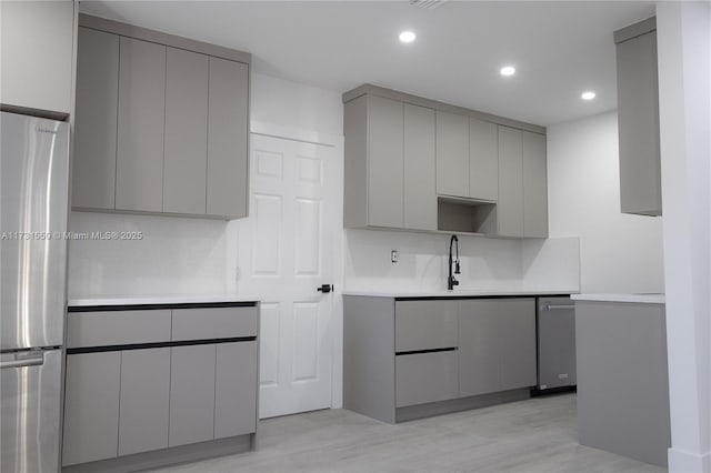 kitchen featuring tasteful backsplash, appliances with stainless steel finishes, sink, and gray cabinetry