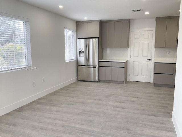 kitchen with gray cabinets, stainless steel refrigerator with ice dispenser, and plenty of natural light