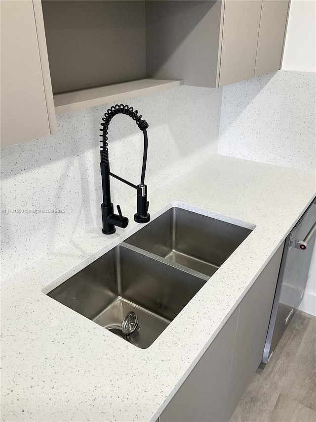 room details featuring sink, light stone counters, gray cabinets, dishwasher, and light hardwood / wood-style floors