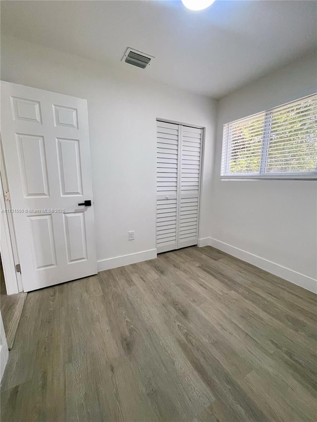 unfurnished bedroom with hardwood / wood-style floors and a closet