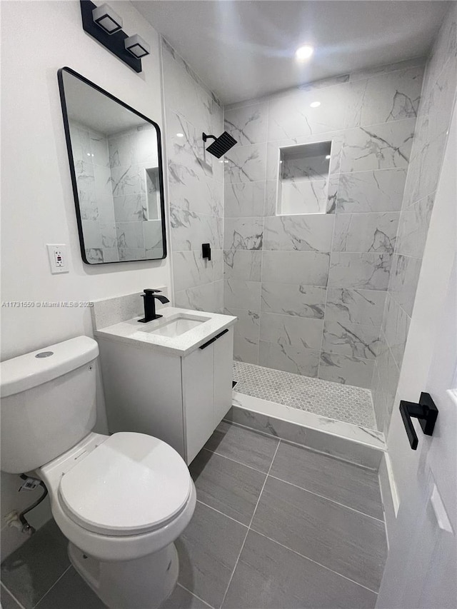 bathroom with vanity, toilet, and tiled shower