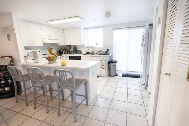 kitchen with light tile patterned floors, a breakfast bar area, white cabinets, kitchen peninsula, and white fridge