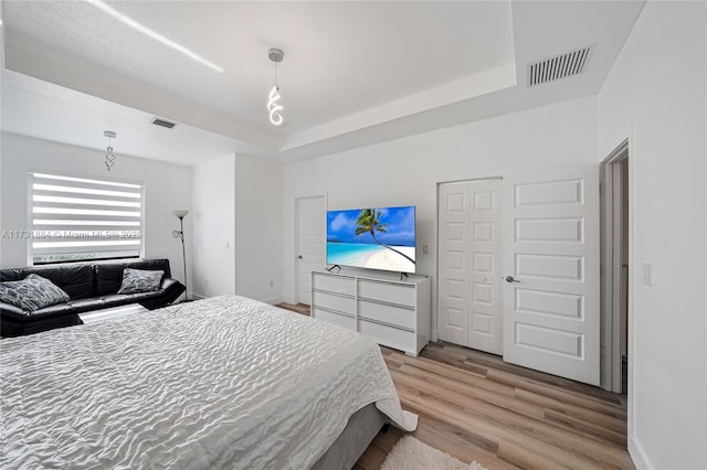 bedroom with a tray ceiling and light hardwood / wood-style flooring