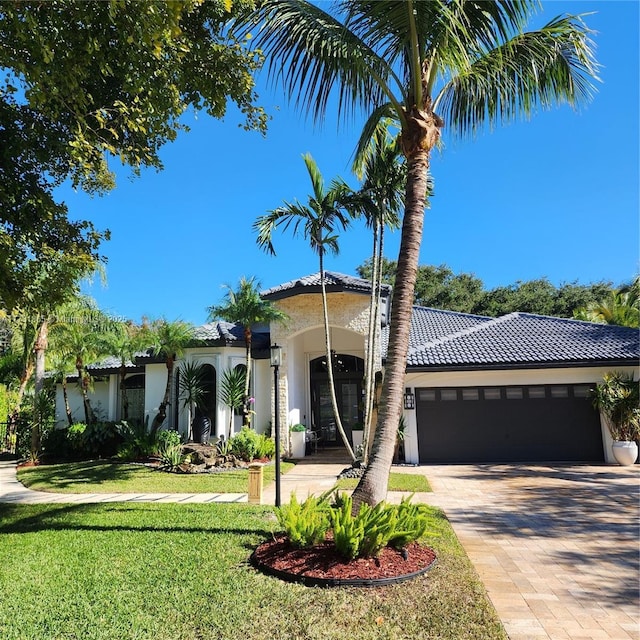 mediterranean / spanish home with a garage and a front lawn