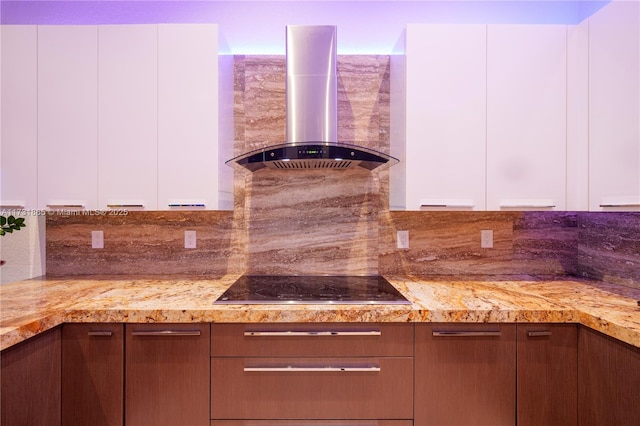 kitchen with white cabinetry, wall chimney exhaust hood, black electric stovetop, and light stone countertops