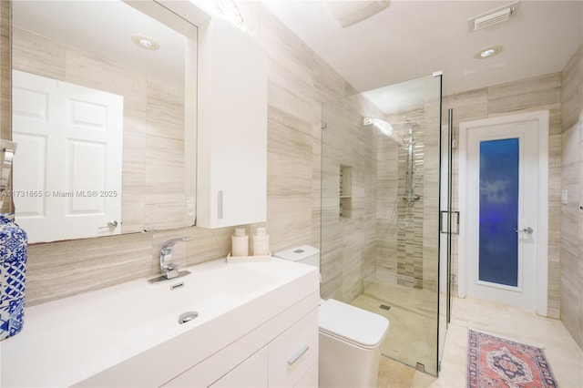 bathroom featuring toilet, a shower with shower door, tasteful backsplash, tile walls, and vanity