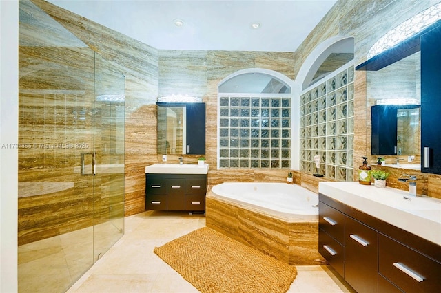 bathroom with independent shower and bath, vanity, tile patterned flooring, and tile walls