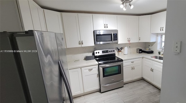 kitchen featuring backsplash, stainless steel appliances, sink, and white cabinets