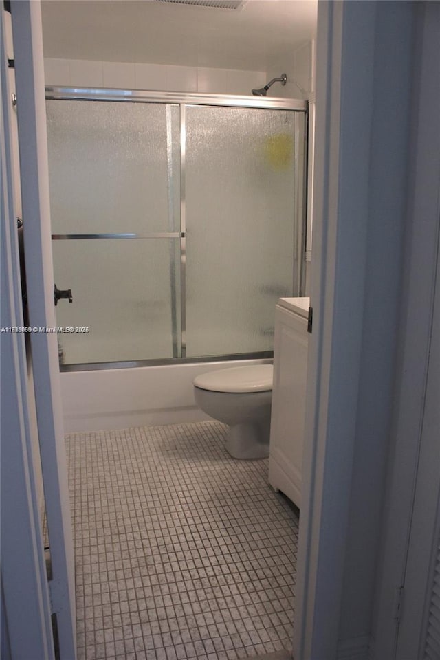 bathroom featuring enclosed tub / shower combo, tile patterned floors, and toilet