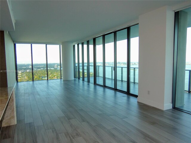 unfurnished room featuring expansive windows, a water view, and light hardwood / wood-style floors