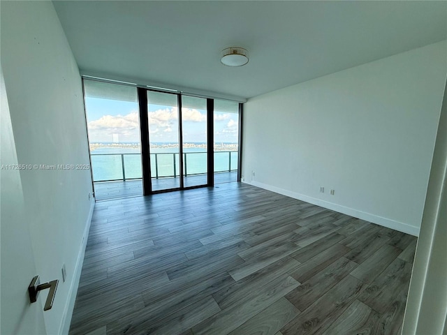 empty room featuring baseboards, wood finished floors, and floor to ceiling windows