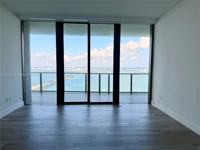 spare room with baseboards, a wealth of natural light, a water view, and floor to ceiling windows
