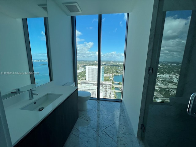 bathroom with a city view, marble finish floor, vanity, and toilet