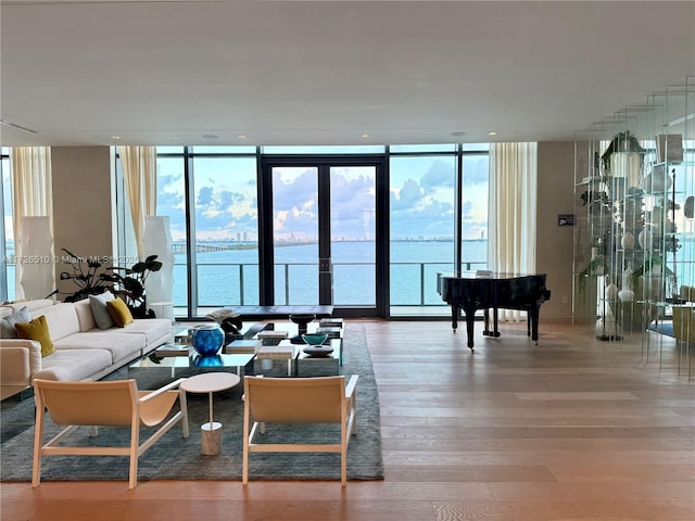 living area featuring expansive windows, light wood-style flooring, a water view, and plenty of natural light
