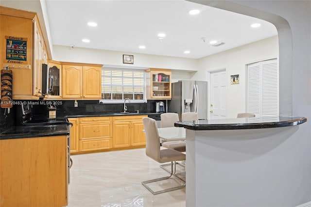 kitchen featuring a breakfast bar, sink, light tile patterned floors, appliances with stainless steel finishes, and decorative backsplash