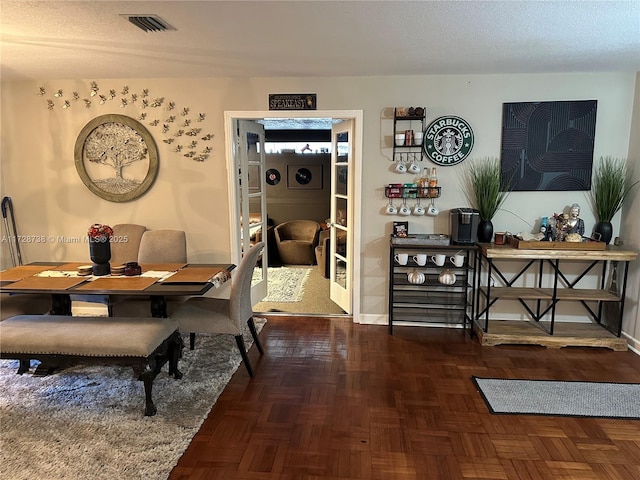 dining room featuring dark parquet flooring and a textured ceiling