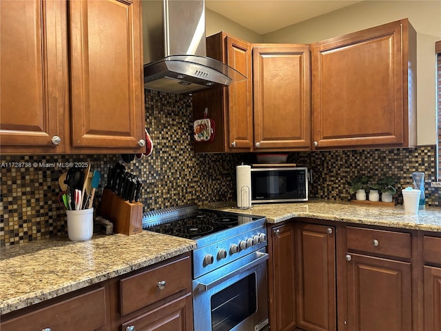 kitchen featuring tasteful backsplash, wall chimney range hood, stainless steel range oven, and light stone counters