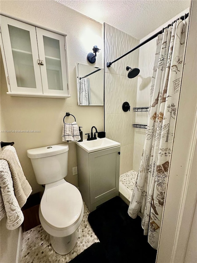 bathroom featuring vanity, toilet, a shower with shower curtain, and a textured ceiling