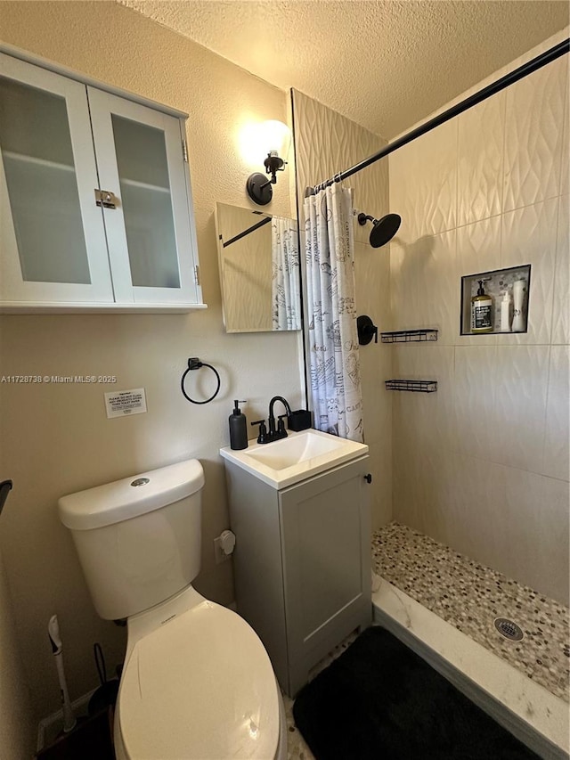 bathroom with vanity, toilet, a textured ceiling, and walk in shower