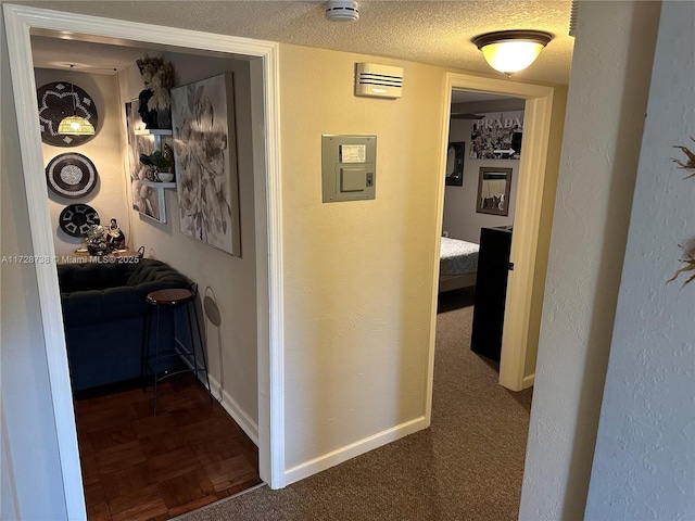 hall with dark colored carpet, electric panel, and a textured ceiling