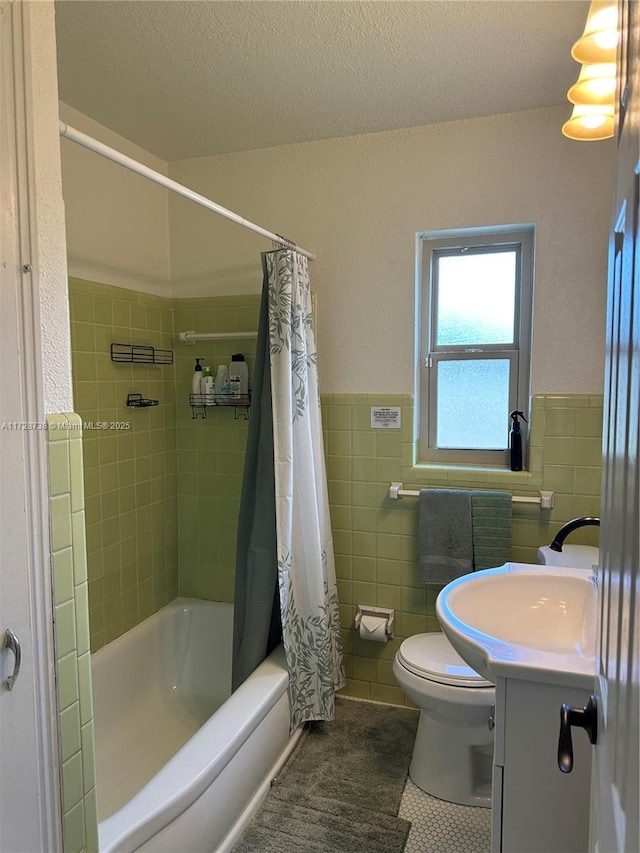 full bathroom featuring tile walls, shower / tub combo, vanity, a textured ceiling, and tile patterned floors