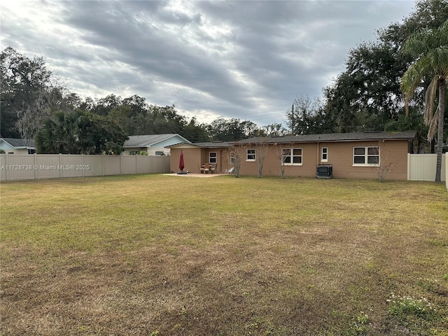 rear view of property featuring a yard and central air condition unit