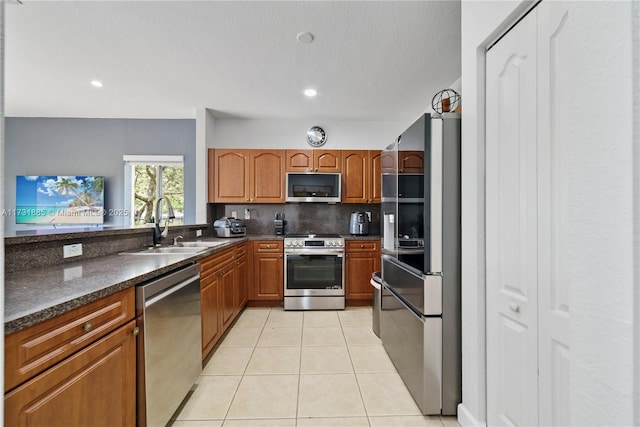 kitchen featuring backsplash, stainless steel appliances, sink, and light tile patterned floors