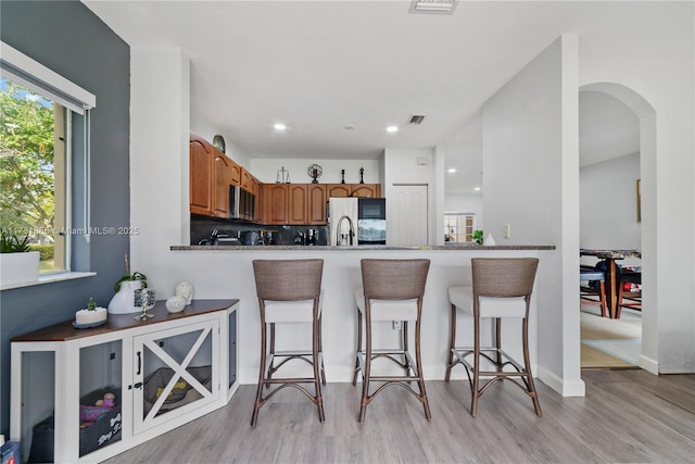 kitchen with backsplash, light wood-type flooring, kitchen peninsula, and a kitchen bar