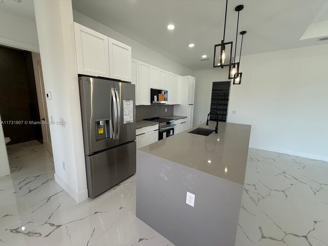 kitchen featuring sink, appliances with stainless steel finishes, an island with sink, white cabinets, and decorative light fixtures