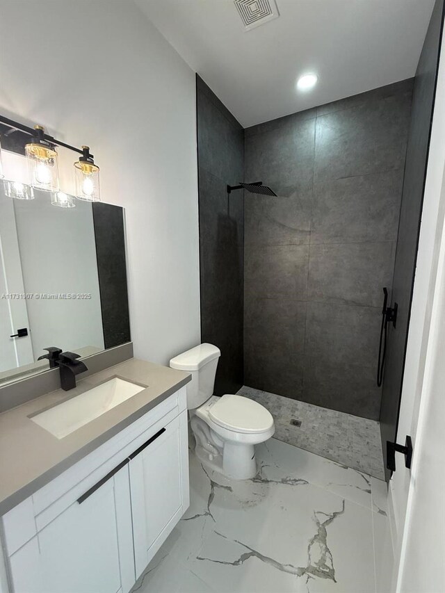 bathroom with vanity, toilet, and tiled shower