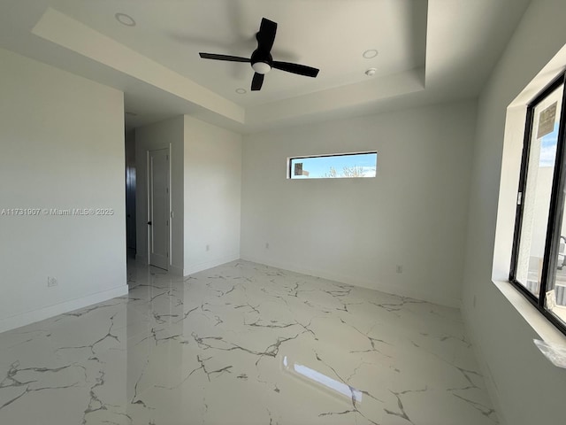 unfurnished room with ceiling fan and a tray ceiling