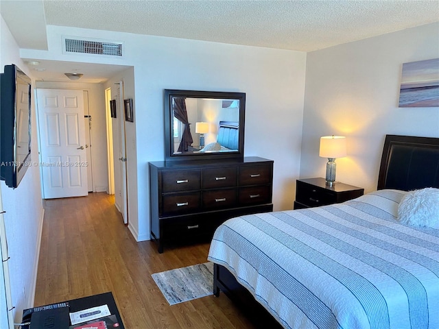 bedroom with a textured ceiling and light hardwood / wood-style flooring