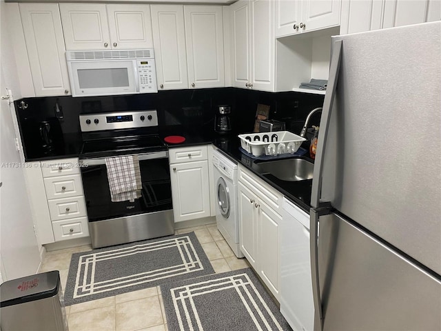 kitchen with sink, stainless steel electric range, light tile patterned floors, fridge, and washer / clothes dryer