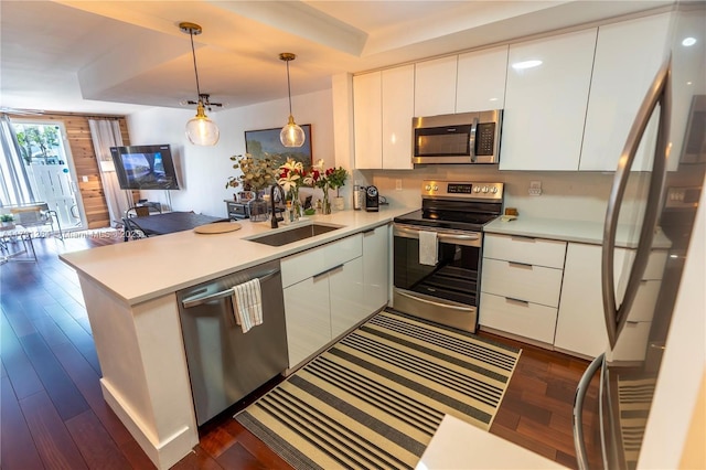 kitchen featuring appliances with stainless steel finishes, white cabinetry, sink, hanging light fixtures, and kitchen peninsula