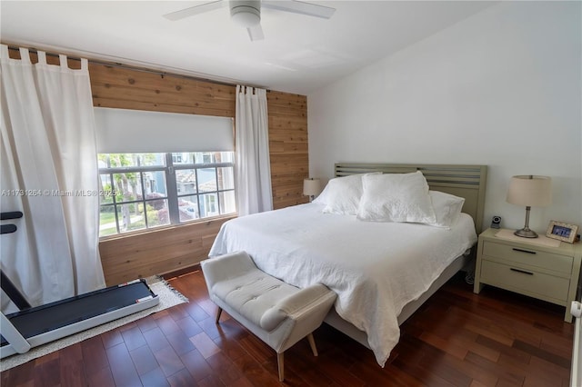 bedroom with dark wood-type flooring, ceiling fan, and wooden walls