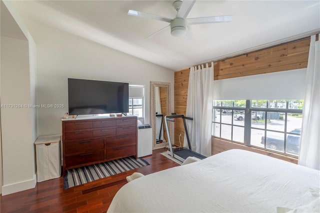 bedroom featuring wooden walls, ceiling fan, dark hardwood / wood-style flooring, and vaulted ceiling