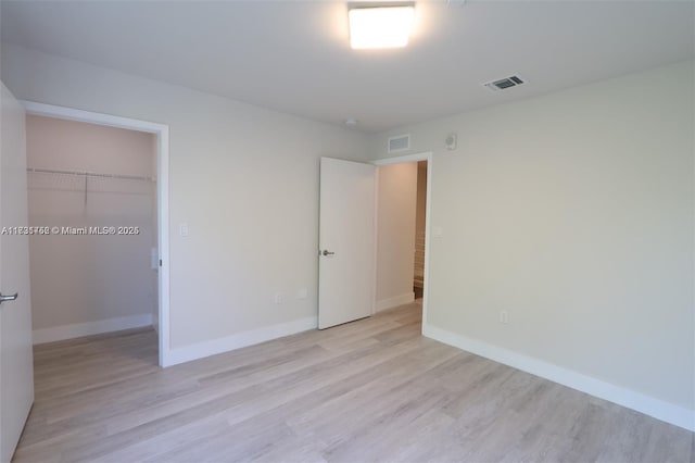 unfurnished bedroom with a spacious closet, light hardwood / wood-style floors, and a closet