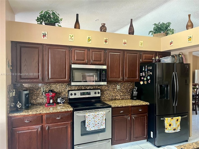 kitchen with light tile patterned flooring, appliances with stainless steel finishes, decorative backsplash, light stone countertops, and a textured ceiling