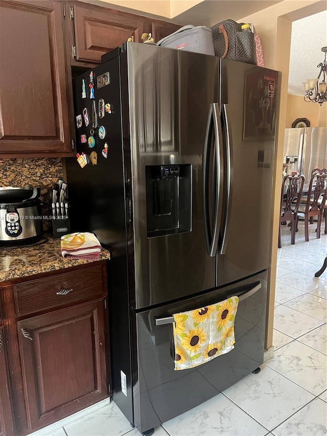 kitchen with dark stone countertops, stainless steel refrigerator with ice dispenser, fridge with ice dispenser, tasteful backsplash, and dark brown cabinetry