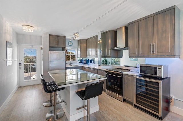 kitchen featuring wall chimney range hood, white refrigerator, range with electric stovetop, a kitchen island, and beverage cooler