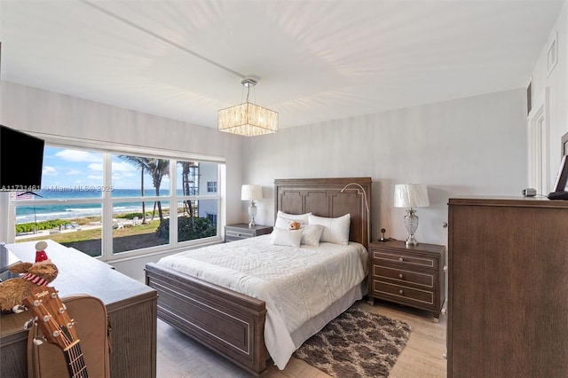 bedroom with a water view, a chandelier, and light hardwood / wood-style floors