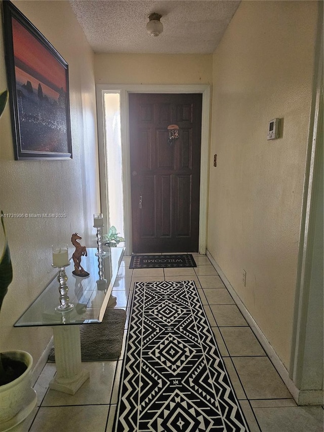 entryway with a textured ceiling and light tile patterned floors