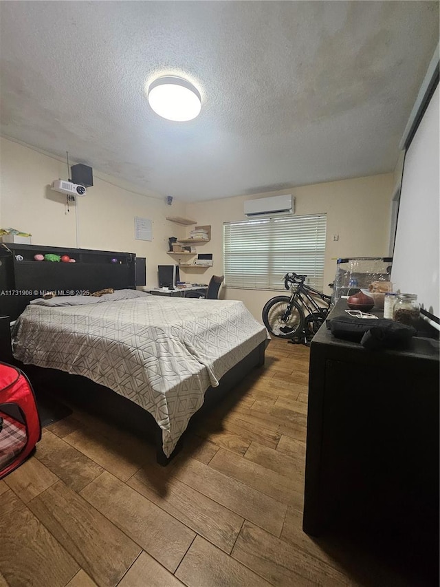 bedroom with an AC wall unit and a textured ceiling