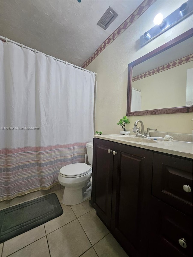 bathroom featuring tile patterned flooring, vanity, a textured ceiling, and toilet